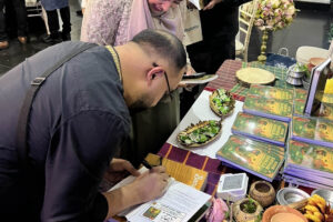Ruhul Amin signing Amar Shonar Bangla book at a cultural event